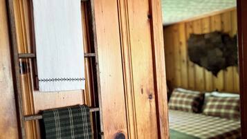 Un intérieur en bois comprenant un lit, une échelle et une étagère avec une serviette et un objet décoratif.