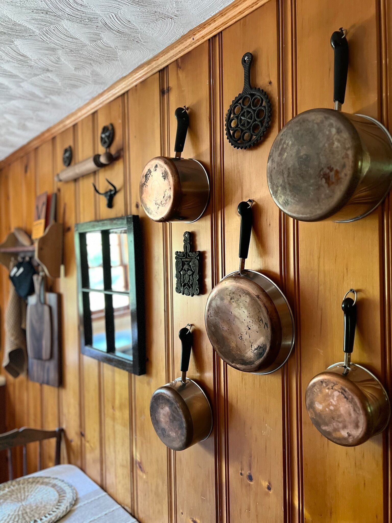 A kitchen with wooden paneling and hanging pots.