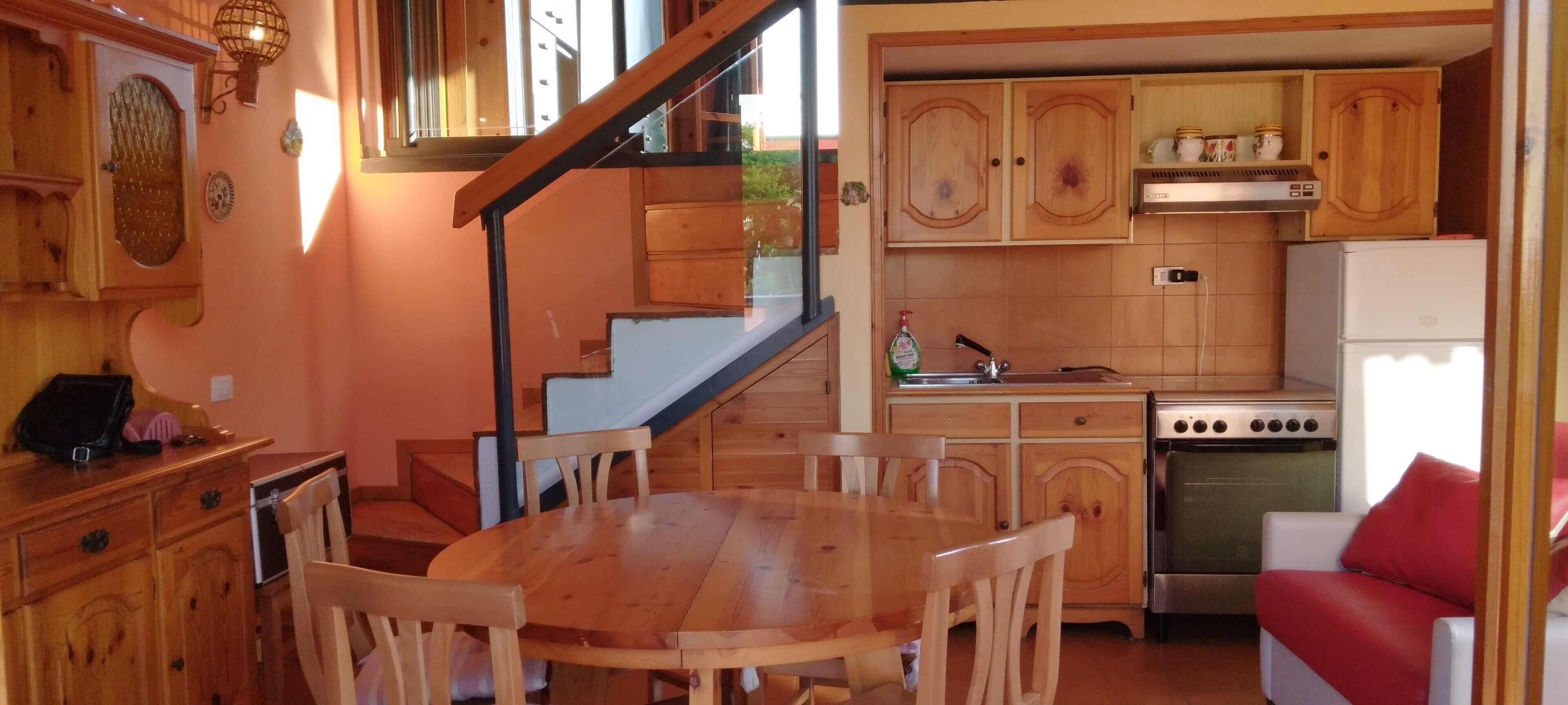 Une cuisine avec des meubles en bois, une table à manger avec des chaises, une cuisinière et un réfrigérateur.
