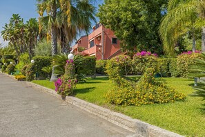 Un quartier résidentiel avec un bâtiment rouge, une végétation luxuriante et une pelouse bien entretenue.
