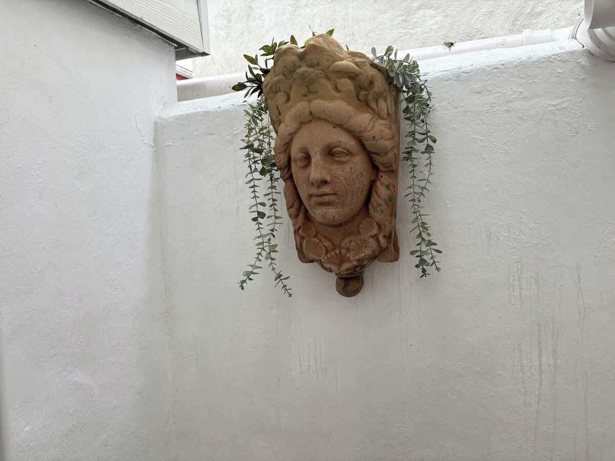 A stone wall-mounted sculpture with foliage.