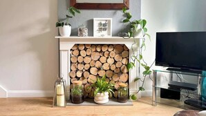Un salón con chimenea, televisor y varios objetos decorativos.