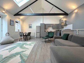 A modern interior with a dining area, sofa, and kitchen. - Stunning Reverse Level Townhouse in Penzance (Penzance)