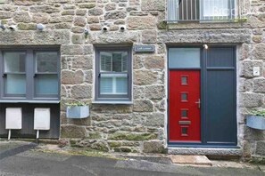 A stone building with a red door and a sign that reads 'Loft Lowen'. - Stunning Reverse Level Townhouse in Penzance (Penzance)