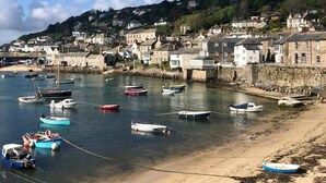 A coastal town with a harbor filled with boats, stone buildings, and a sandy beach. - Janies Cottage- Eclectic Interiors & Vintage charm (Mousehole)