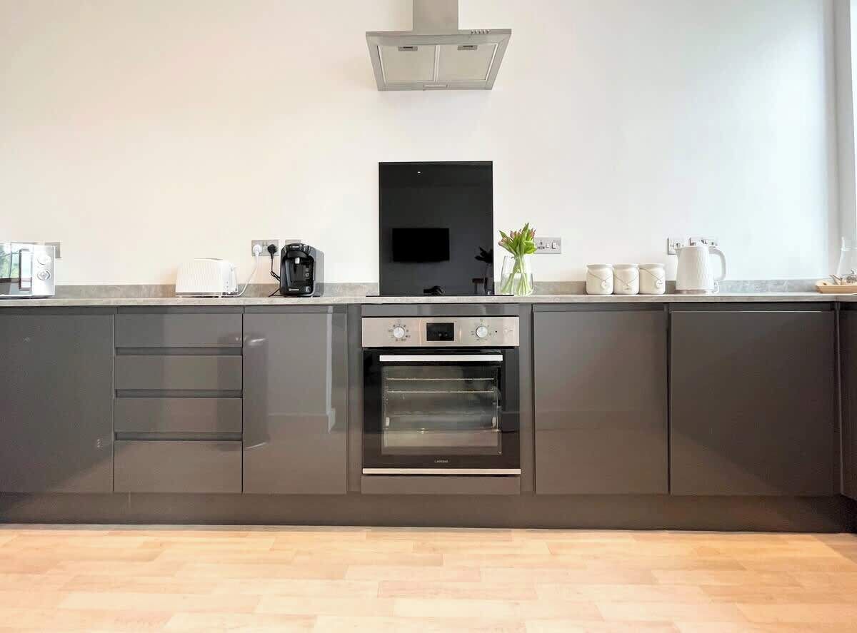 A modern kitchen with a built-in oven, a coffee maker, and a flat-screen TV.