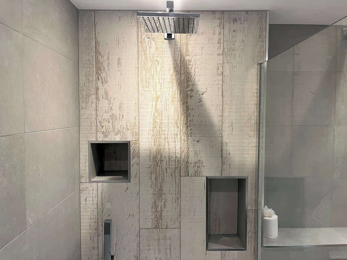 Une salle de bain moderne dotée d’une grande zone de douche, d’une paroi de verre et de compartiments de rangement intégrés.