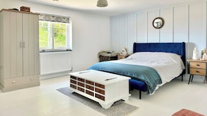 Une chambre à coucher avec un lit, une armoire, une table de chevet et une fenêtre.