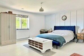 A bedroom with a bed, a wardrobe, a bedside table, and a window.