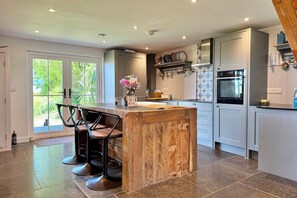 A modern kitchen with a central island, bar stools, a built-in oven, and a large window.
