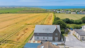 Un paysage rural avec un grand b âtiment, de vastes champs et une vue lointaine sur la mer.
