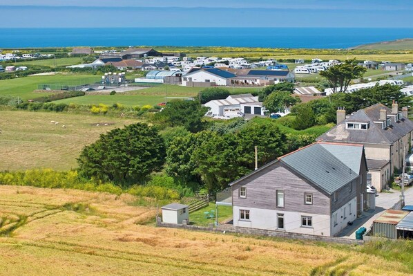 A coastal residential area with houses, a grassy field, and a view of the sea.
