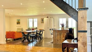 Un vaste espace de vie comprenant une table à manger, des chaises, un canapé et un escalier.