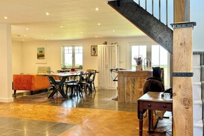 A spacious living area with a dining table, chairs, a sofa, and a staircase.
