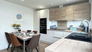 Una cocina moderna con armarios de madera, horno empotrado y una isla grande con lavaplatos.