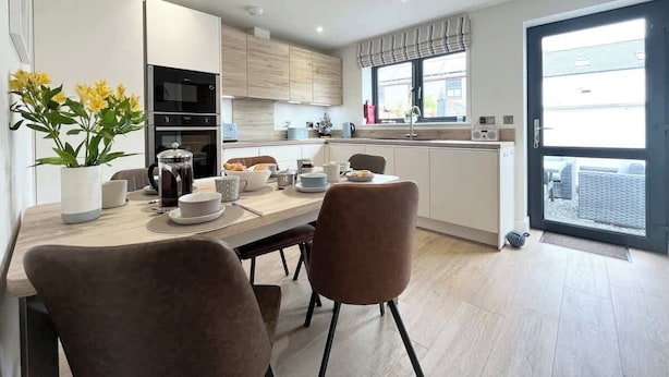 Una cocina moderna con comedor, que cuenta con un amplio ventanal, electrodomésticos integrados y un ambiente informal.