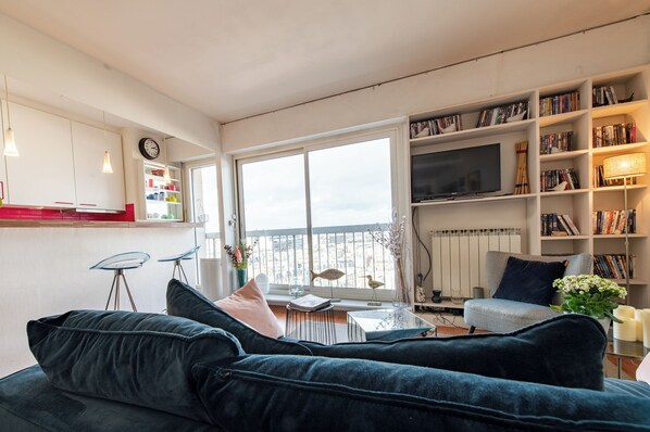 A modern living room with a dark blue sofa, a coffee table, and a bookshelf filled with books.