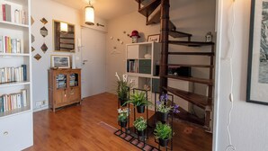 Una habitación con una escalera de madera, una estantería y varias plantas en macetas.