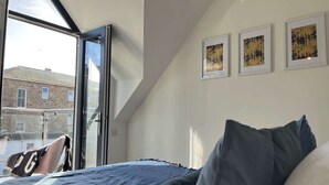 Un dormitorio con una cama, una ventana y tres cuadros en la pared.