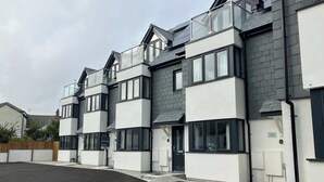 Un edificio residencial moderno de varios pisos con techo plano, ventanas amplias y entrada pavimentada.