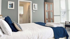Une chambre à coucher avec un grand lit, une armoire en bois et une porte donnant sur une salle de bain.
