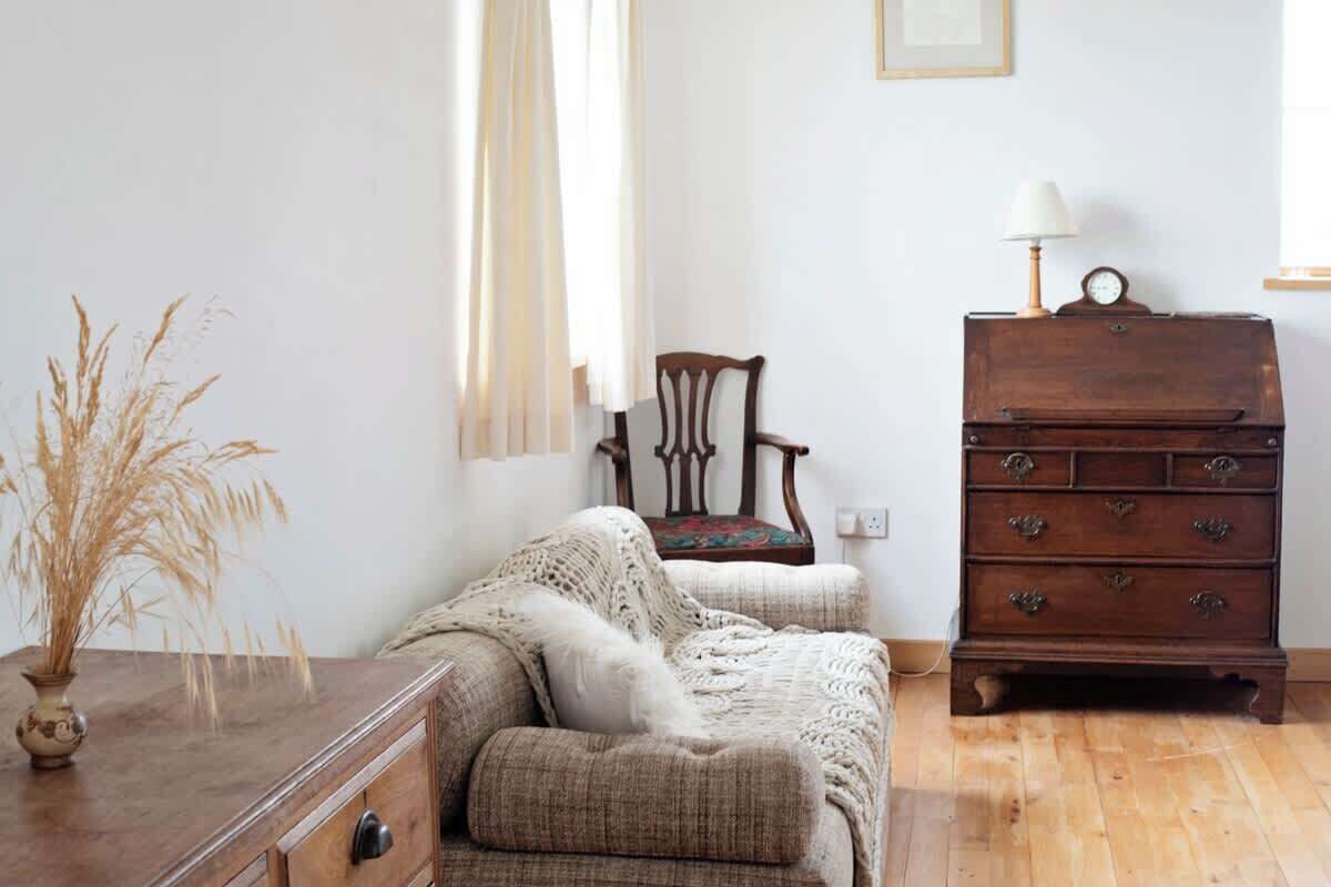 Een kamer met een houten dressoir, een stoel en een bank.