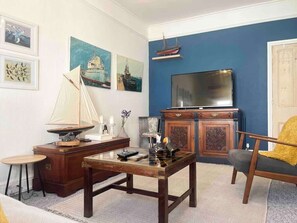 A living room with a wooden coffee table, a television, and a sailboat model.