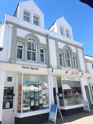 A white building with a travel agency and an Indian takeaway restaurant on the ground floor. - Charming 2-Bed Artist's Residence Central Penzance (Penzance)