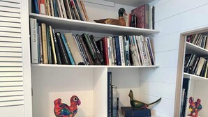 A bookshelf with various books and decorative items. - Charming 2-Bed Artist's Residence Central Penzance (Penzance)