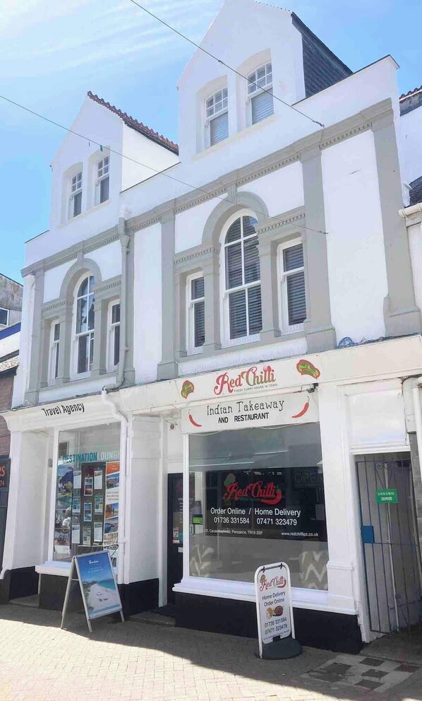 Un edificio de dos pisos con un letrero que dice 'Red Chilli Indian Takeaway and Restaurant' y un letrero de 'Travel Agency' debajo.