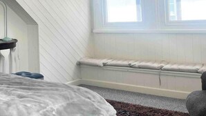 A bedroom with a large window, a bed, a bench, and a ceiling fan. - Charming 2-Bed Artist's Residence Central Penzance (Penzance)