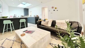 A modern living space with a sofa, coffee table, and bar stools. - Stunning 1 Bed~ River view~ parking~central (Newlyn)