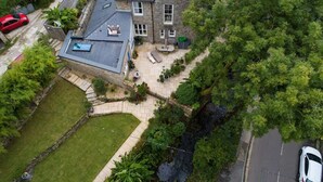 An aerial view of a house with a sloped roof, a patio with outdoor furniture, and a small garden area. - Stunning 1 Bed~ River view~ parking~central (Newlyn)