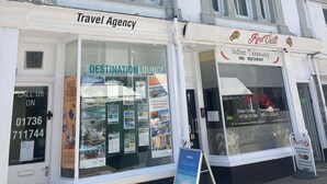 A white building with a travel agency and an Indian takeaway restaurant.