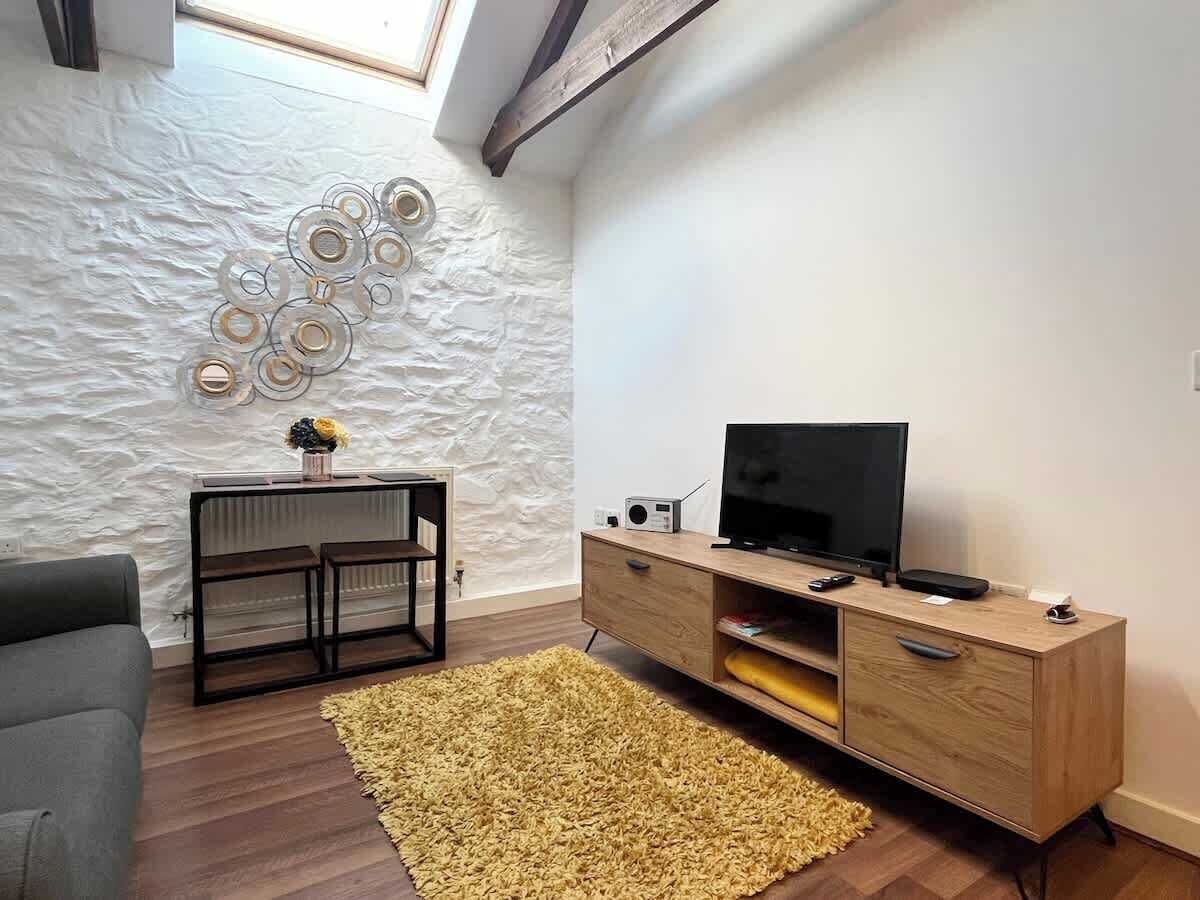 A living room with a modern design, featuring a wooden TV stand, a sofa, and a decorative wall.