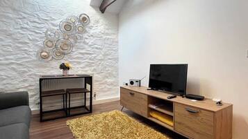 A living room with a modern design, featuring a wooden TV stand, a sofa, and a decorative wall.