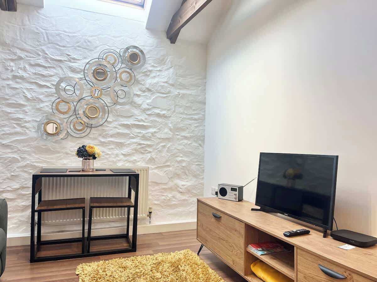 A modern living room with a television, a wooden cabinet, and a decorative wall.