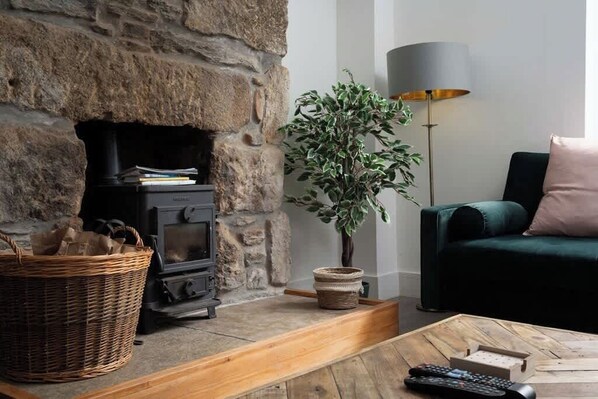 Una sala de estar acogedora con una chimenea de piedra, un sofá verde, una lámpara de pie y una mesa de centro.