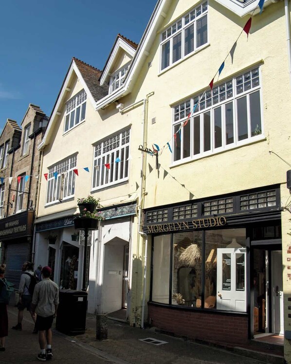 A building with a shop named 'Morgelyn Studio' on the ground floor, featuring large windows and a display window with items.
