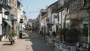 A street lined with cafes and shops, featuring outdoor seating and a variety of storefronts. - Contemporary Apartment in central Penzance (Penzance)