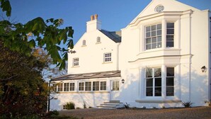 A white two-story house with a large bay window on the right side.