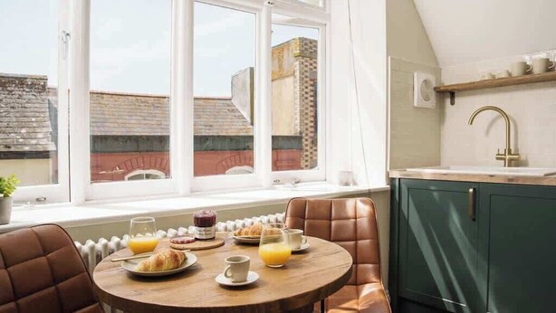 Une table dressée pour le petit-déjeuner, avec des chaises et une vue sur l’extérieur.