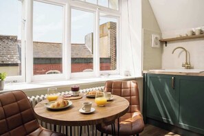 A breakfast setup with a table, chairs, and a view of the outside. - Trendy Refurbished Apartment in Central Penzance (Penzance)