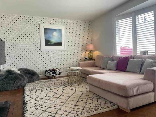 A living room with a patterned wall, a sofa, a rug, a lamp, and a framed picture.