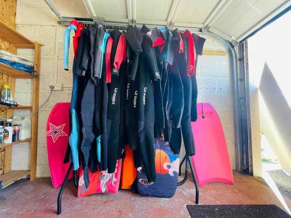 Un'area di stoccaggio con tavole da surf e mute appese a scaffali.