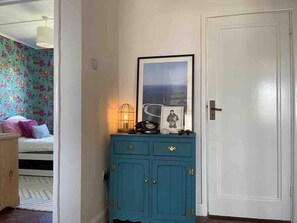 A room with a bed, a blue cabinet with a framed picture, and a white door.
