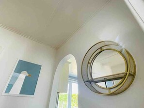 Una habitación con un espejo redondo en la pared, un cuadro enmarcado y un arco de entrada.