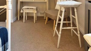 A cozy attic bedroom with a vanity, chair, and a small table. - Waterfront Cottage by Whitby Harbour + (Whitby)