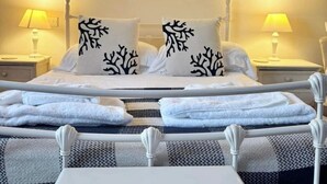 A bedroom with a bed, two nightstands, two lamps, and a bedside table. - Waterfront Cottage by Whitby Harbour + (Whitby)