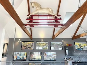 Una habitación con techo de madera, una escultura de un caballo montado y varias fotografías enmarcadas en la pared.